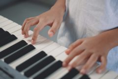 Close up and selective focus on hands and finger of asian little pianist boy while press on key of Piano, playing  to making sound of music